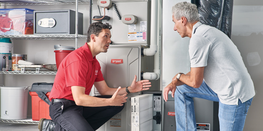 Bryant technician talking with homeowner while checking air filter and furnace