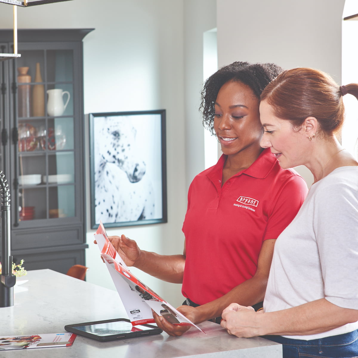 Bryant technician with homeowner outdoors in front of carrier air conditioner